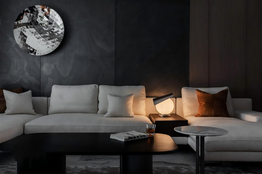 Black ultra-thin natural stone used as a modern living room feature wall with light sofa, warm lighting and refined interior design.