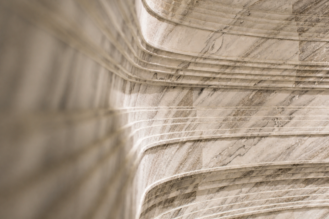 Arctic Storm natural stone veneer used on a curved interior wall with soft lighting and layered stone texture.