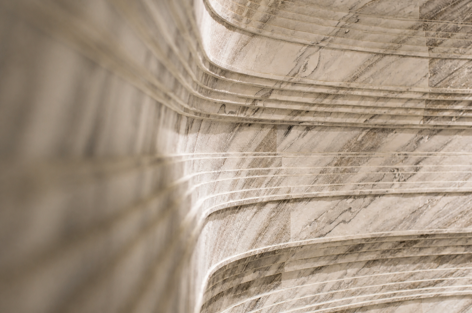 Arctic Storm natural stone veneer used on a curved interior wall with soft lighting and layered stone texture.