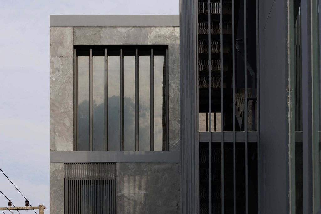 Exterior stone veneer wall with vertical ribbed details and dark gray panel texture