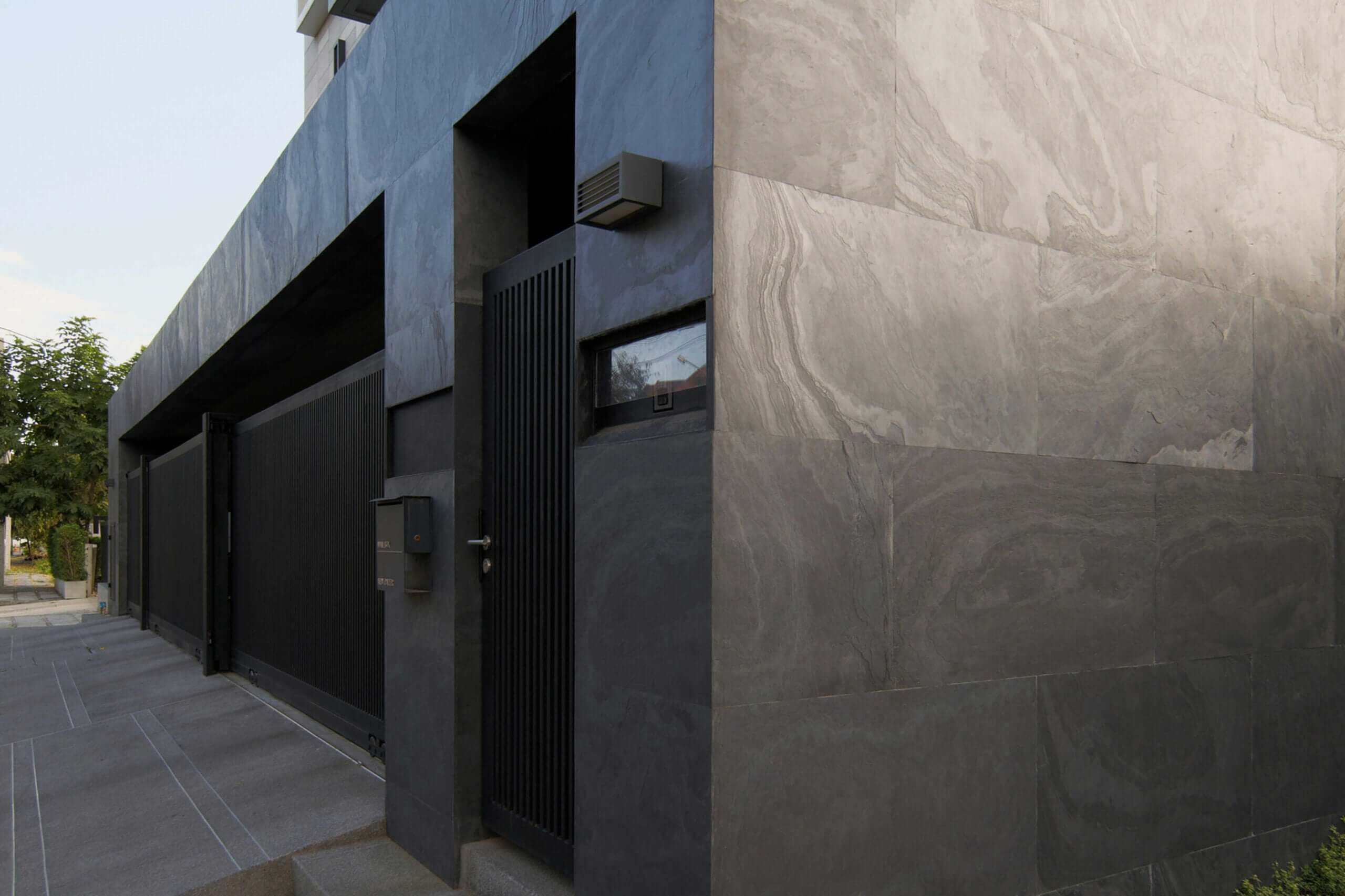 Modern building exterior with black natural stone veneer wall and smooth gray panels