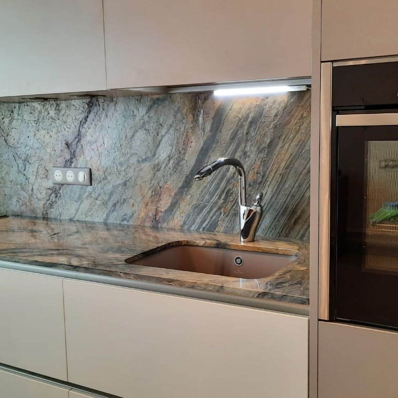 Kitchen backsplash wall covered in blue-gray stone veneer with copper-orange veining