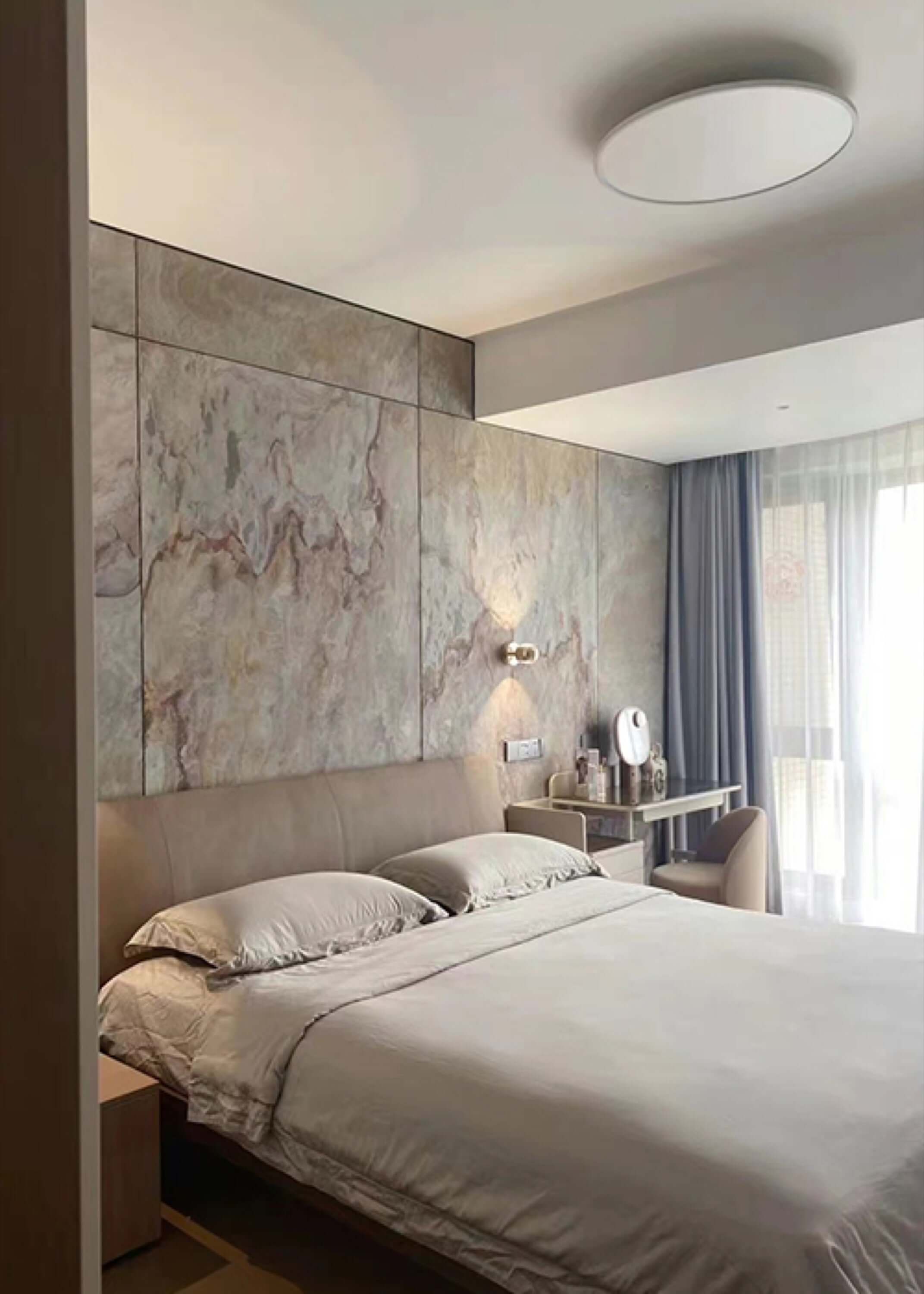 Grey and cream stone veneer feature wall beside a modern bed