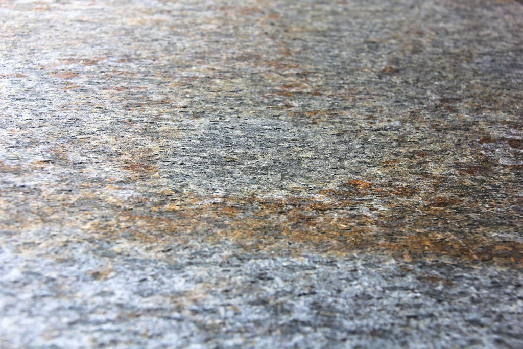 Close-up of gray natural stone veneer with silver-white and warm gold speckles