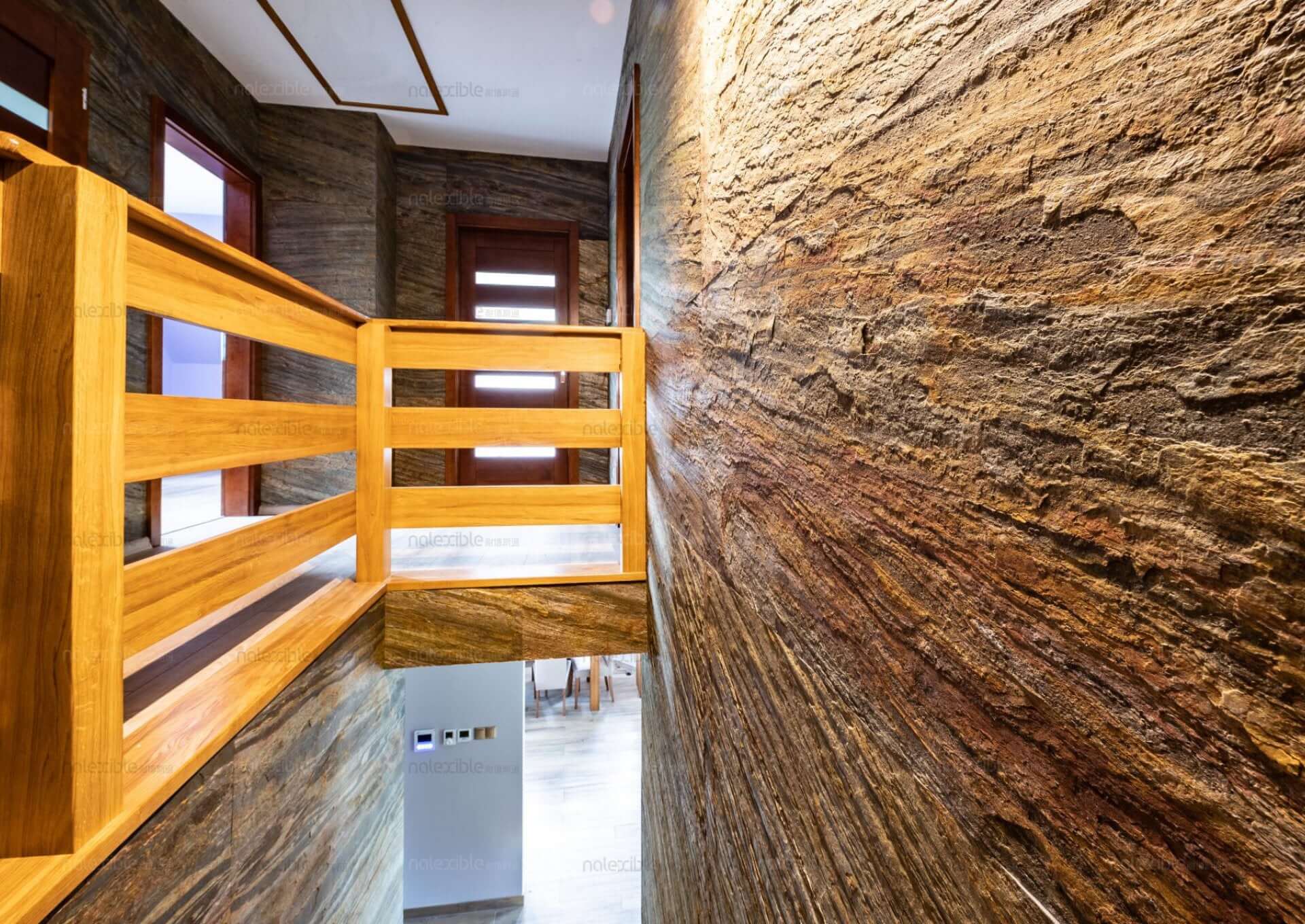 Hallway wall clad in natural stone veneer with blue-gray base and copper-brown veining