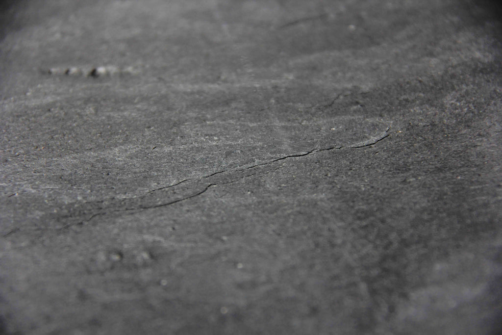 Close-up of black-gray natural stone veneer texture with faint striations