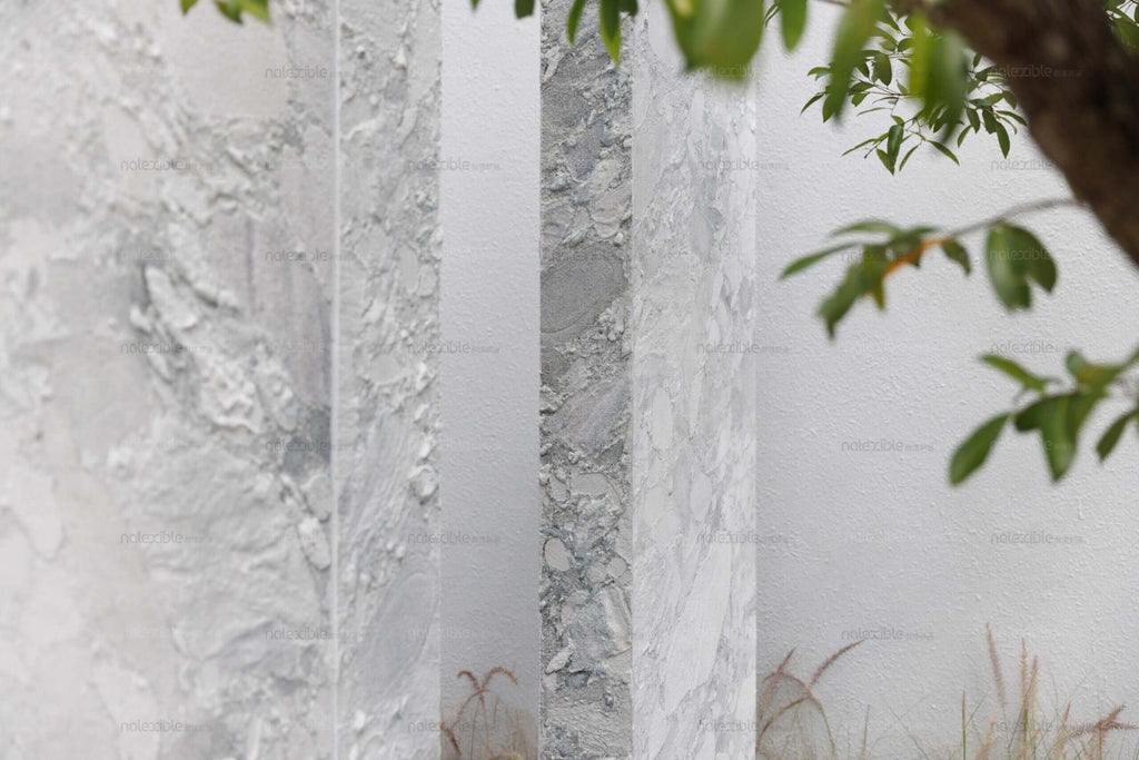 Light gray granite stone veneer panels with textured, marble-like veining close-up.