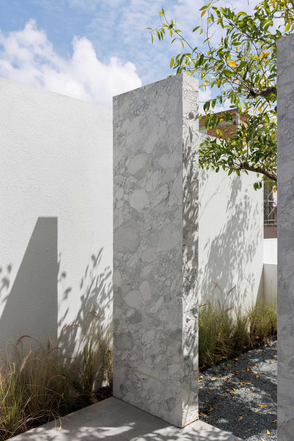 Granite stone veneer corner with light gray marbled texture on tall panel surfaces.