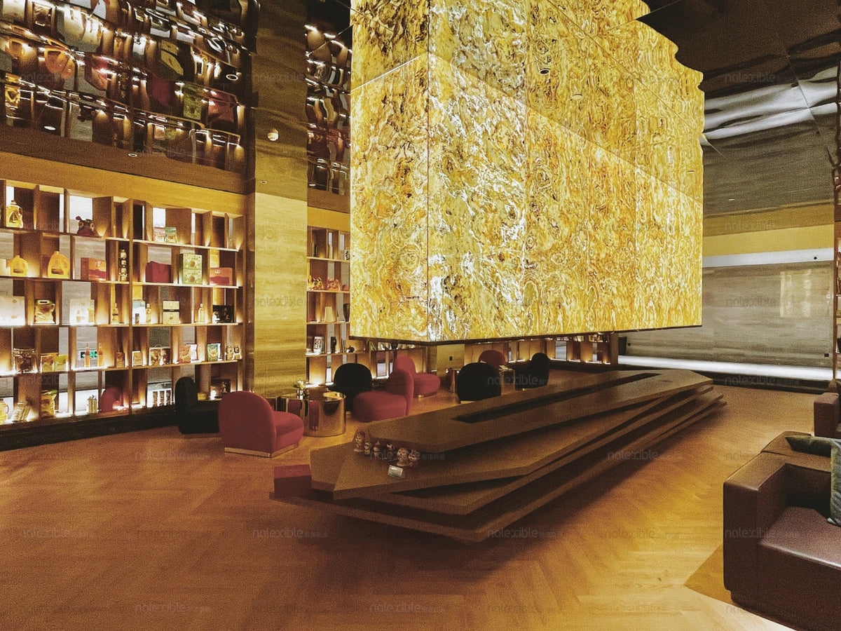 Indian Autumn translucent natural stone panels used as a warm backlit feature in a hotel lobby with timber finishes and lounge seating.