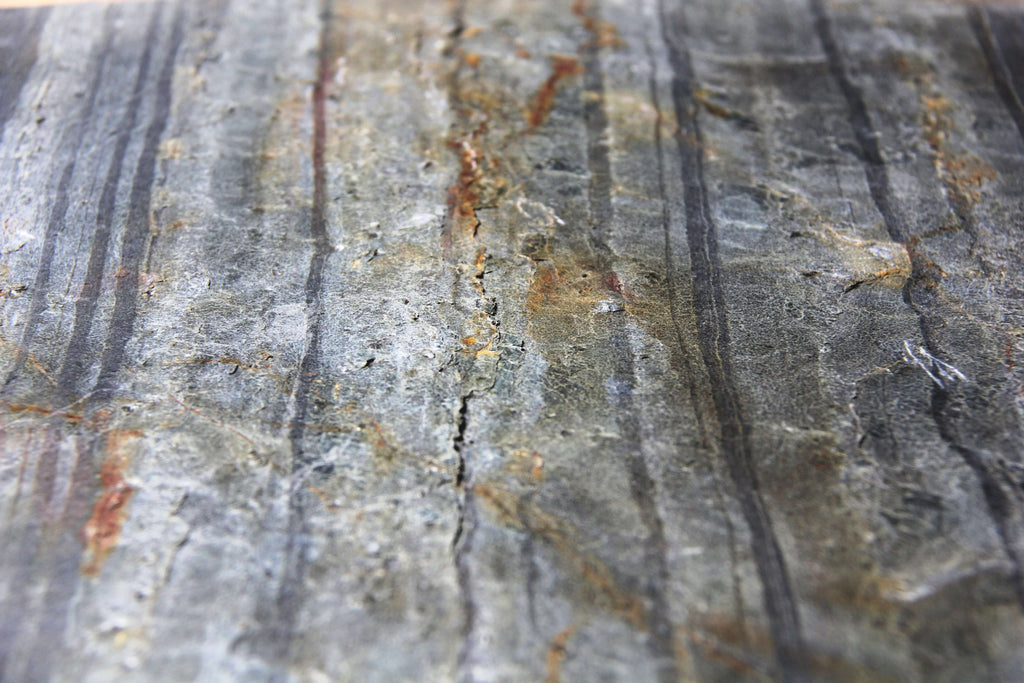 Detail view of blue-gray stone veneer texture with scattered copper-orange spots