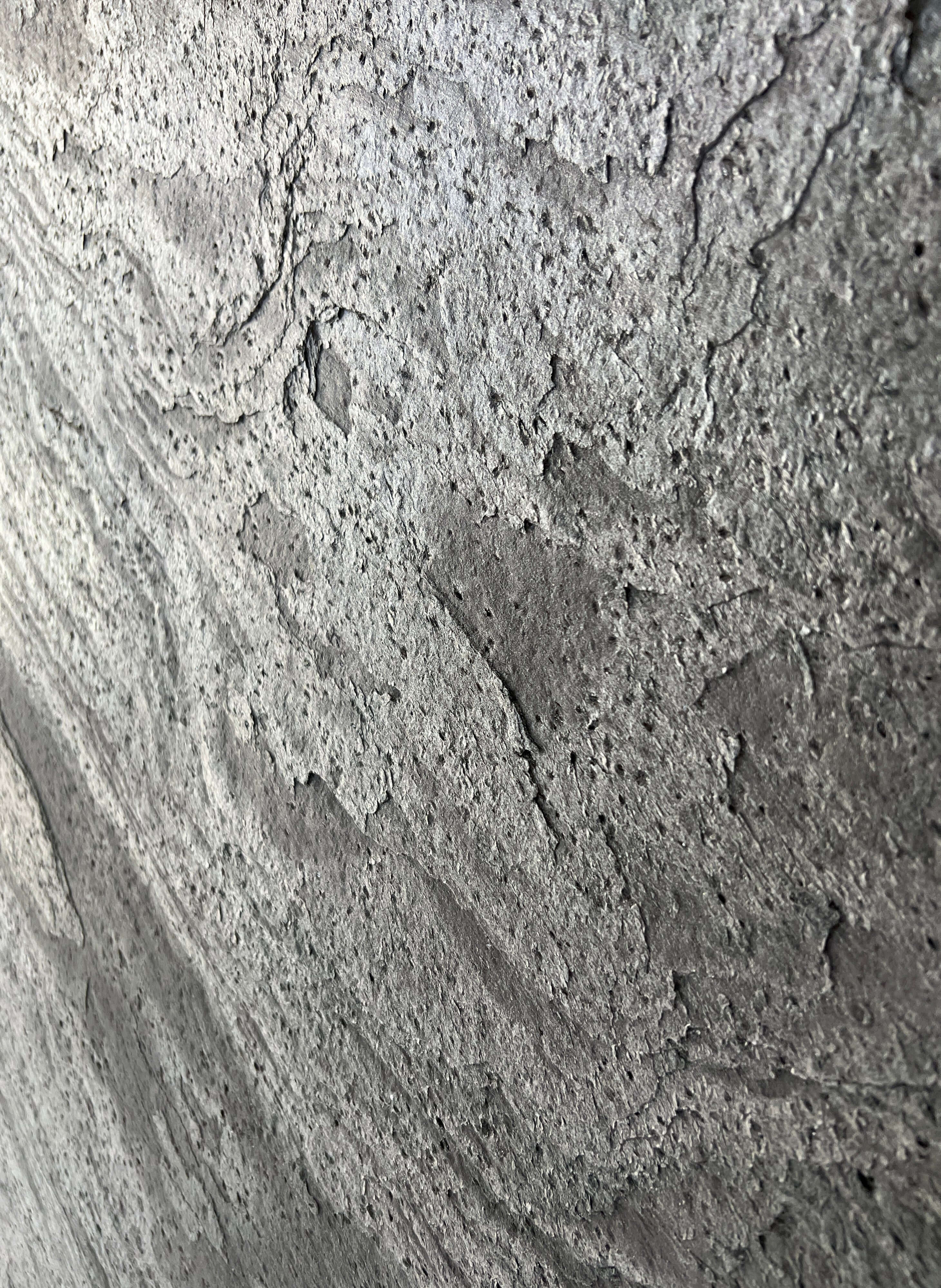 Silver grey natural stone veneer close-up with speckled, pitted stone texture