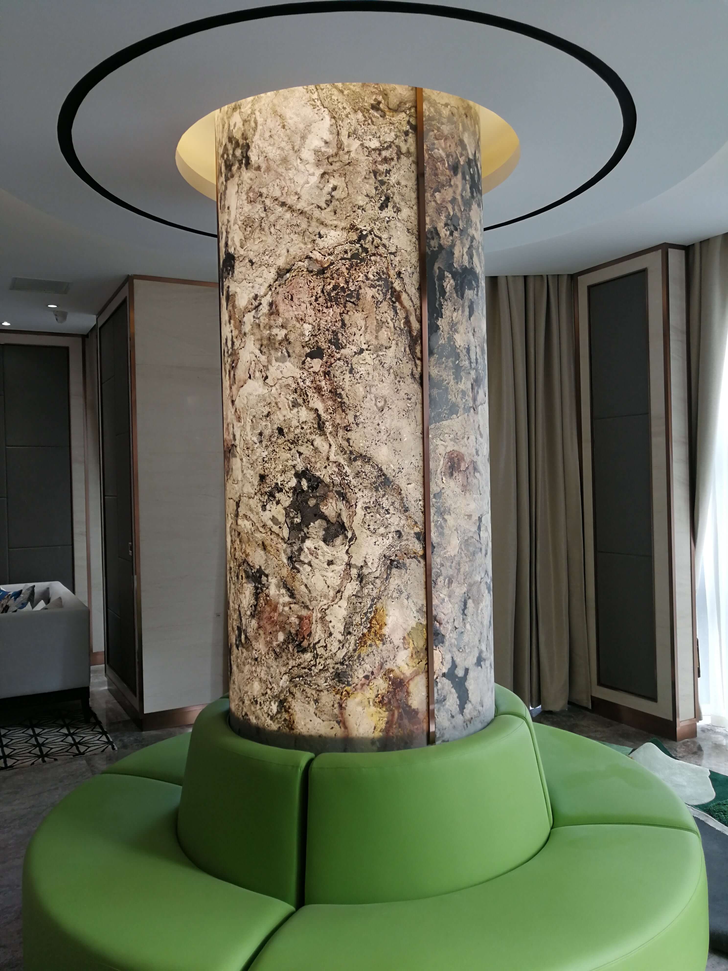 Translucent stone column surface with beige, gray, and brown speckled marbled pattern