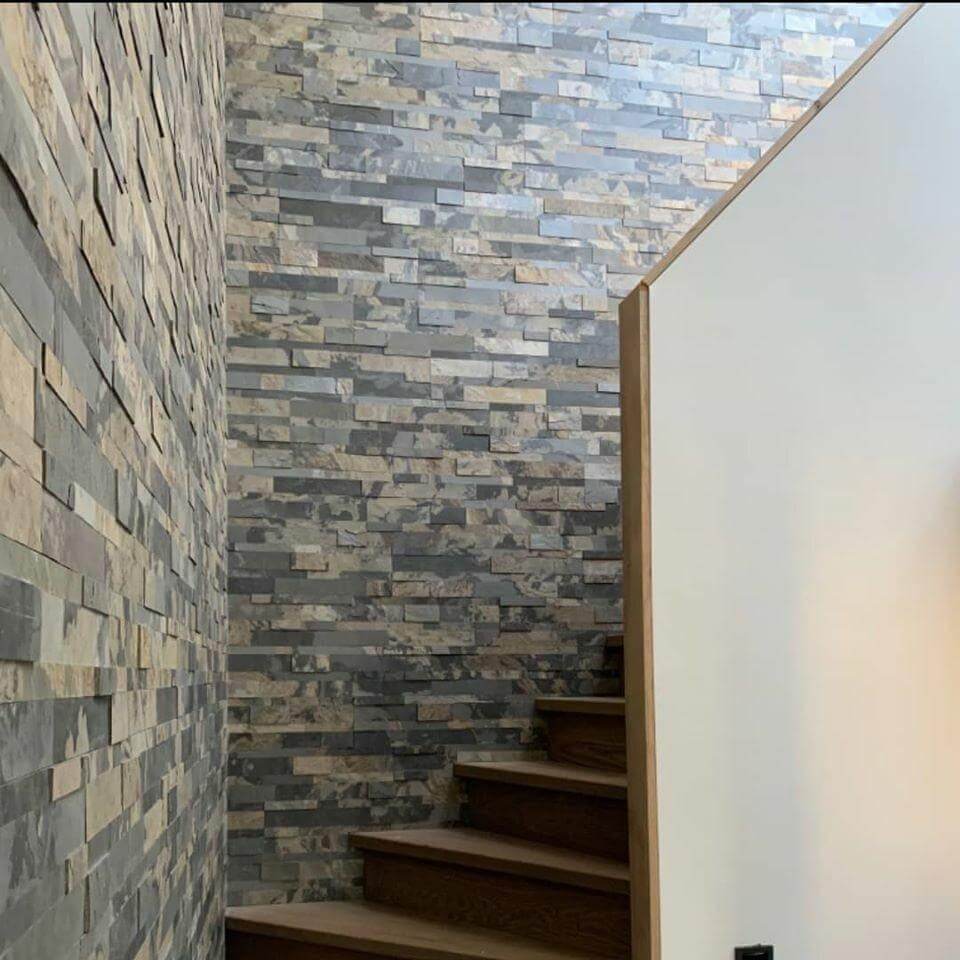 Peel-and-stick stone wall tiles along stairwell walls in gray, charcoal, and tan.