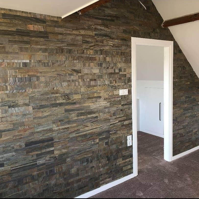 Peel-and-stick stone wall tiles on corner wall with gray, tan, and brown stacked blocks.