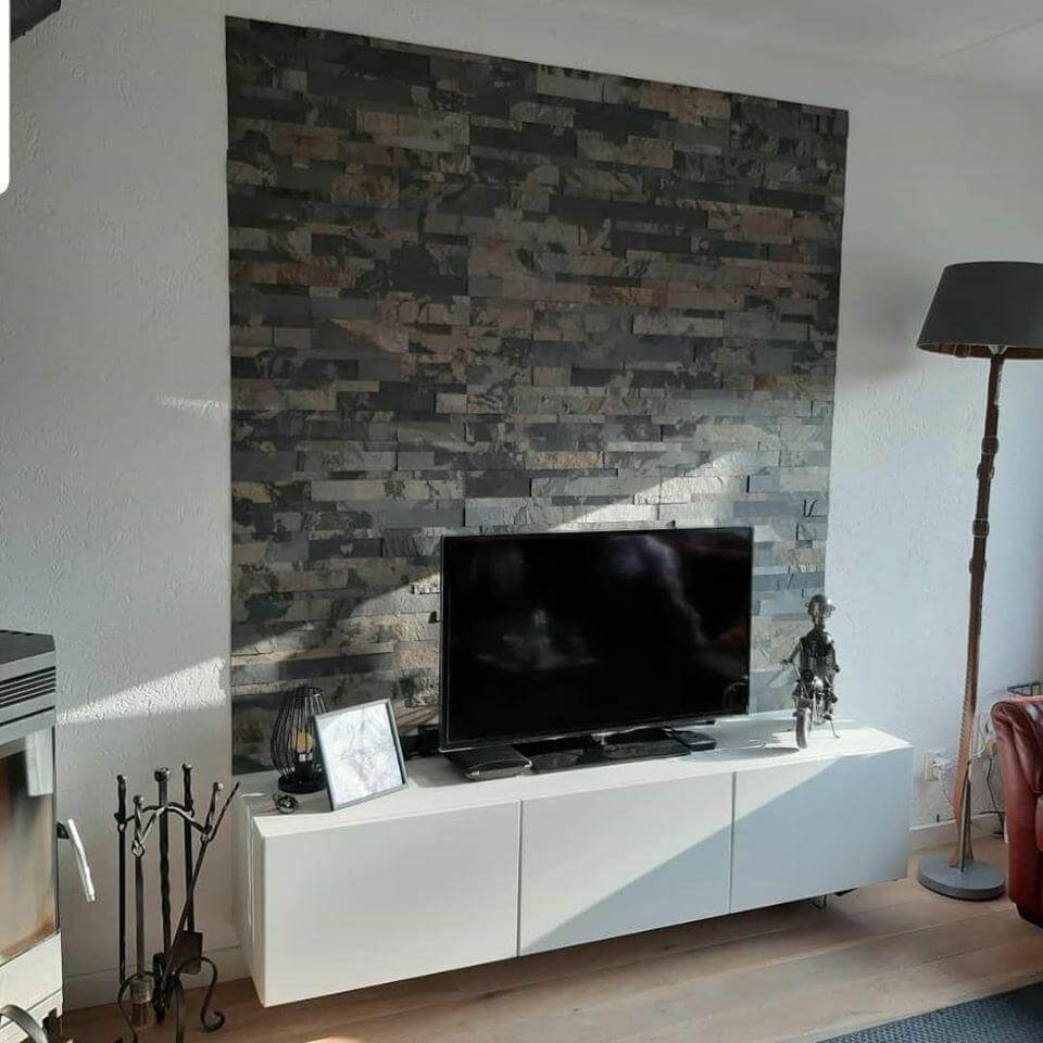 Peel-and-stick stone wall tiles behind TV mantel, gray and brown stacked-stone pattern.