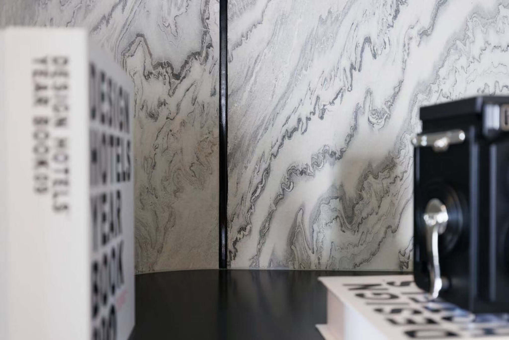 Interior wall paneling of light gray stone veneer with white marble-like swirls