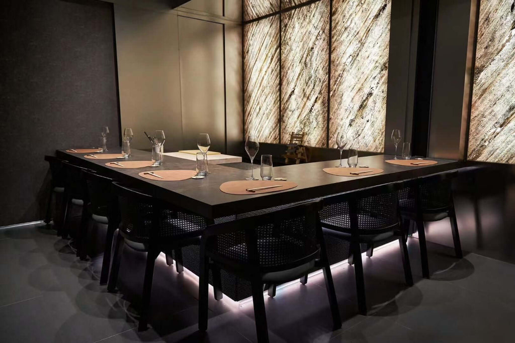 Translucent natural stone sheet wall panels behind set dining table and chairs