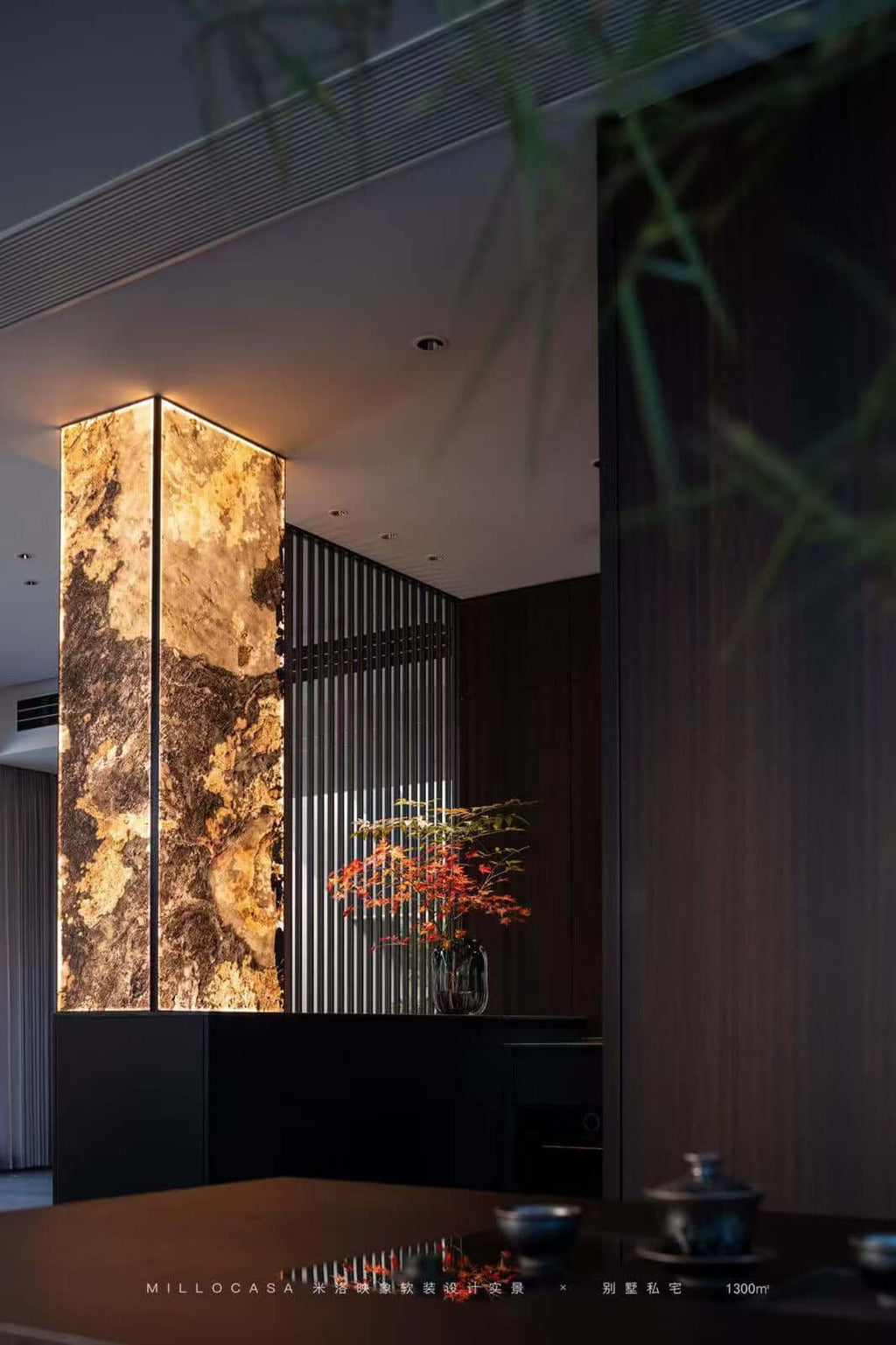 Gold-and-beige stone wall panel with vertical metal grilles in a corridor