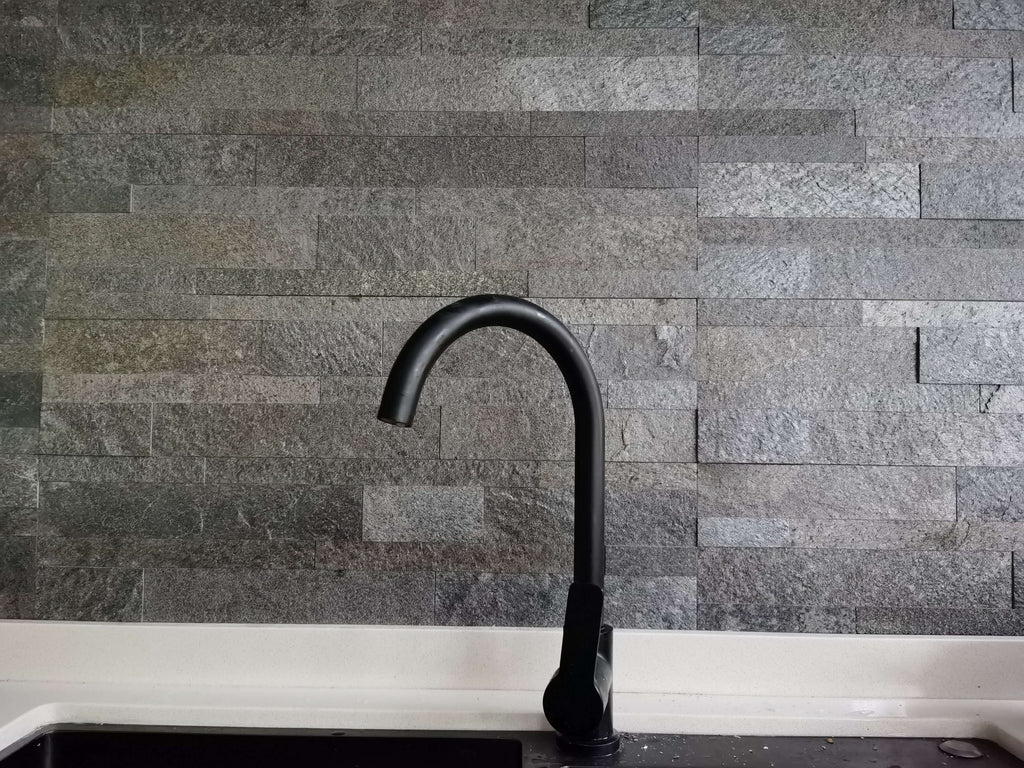 Dark stone tile wall with black curved faucet installed
