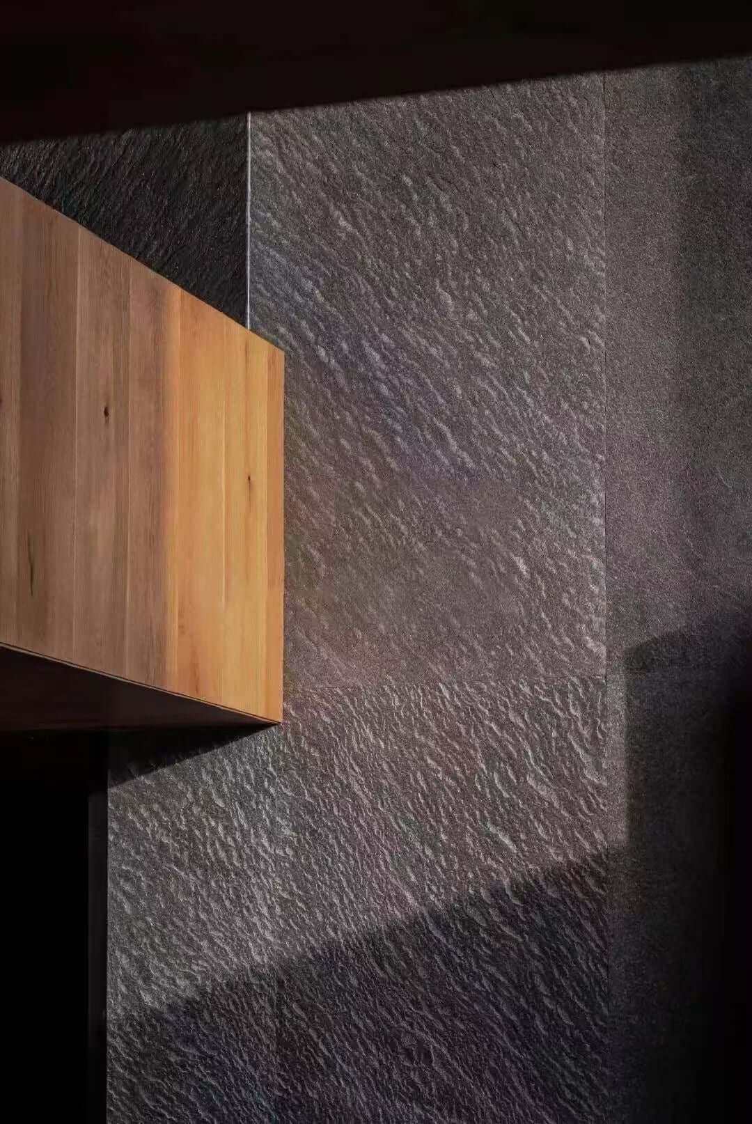 Black natural stone veneer in a corner with textured, slate-like finish