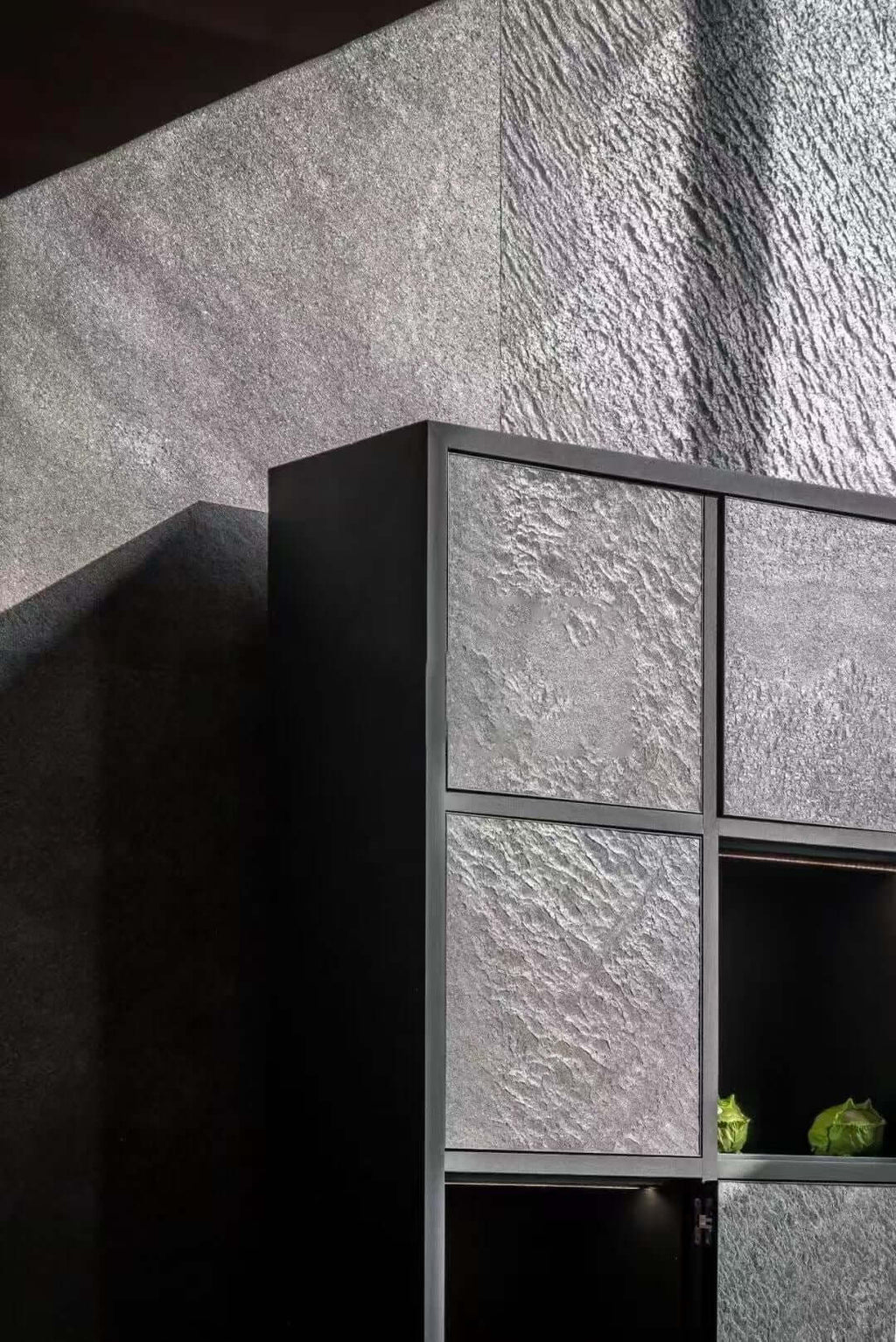 Black stone veneer panels with metal grid lines on a textured wall
