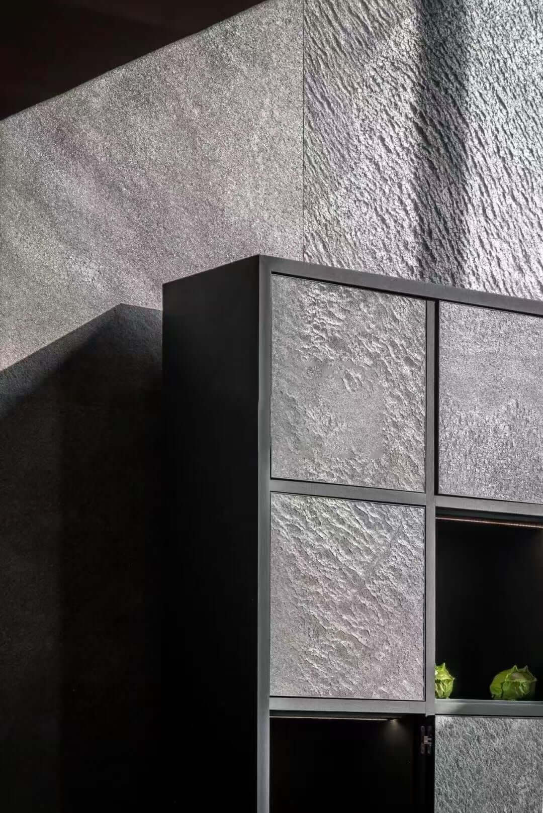 Black stone veneer panels with metal grid lines on a textured wall