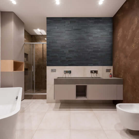 Bathroom vanity wall with dark stone peel-and-stick tiles behind sink and faucets