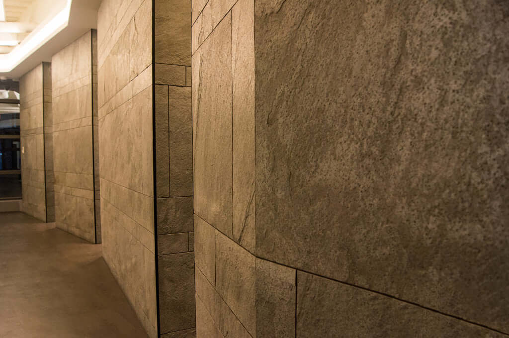 Silver grey natural stone veneer panels lining a corridor wall with grout lines
