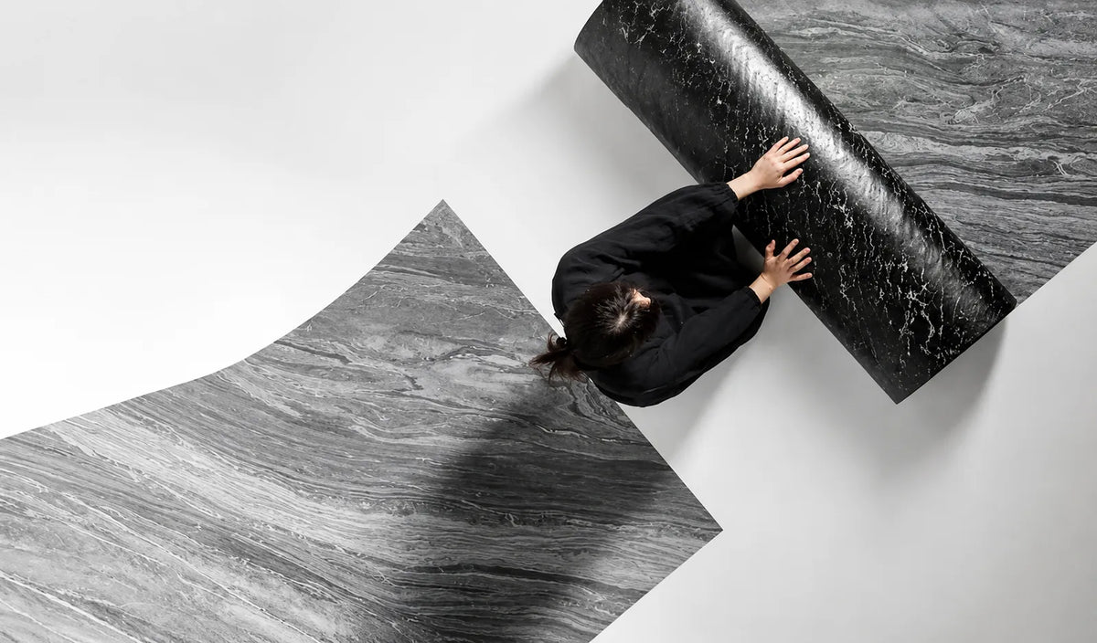 Person demonstrating the flexibility of a dark grey ultra-thin natural stone veneer sheet.