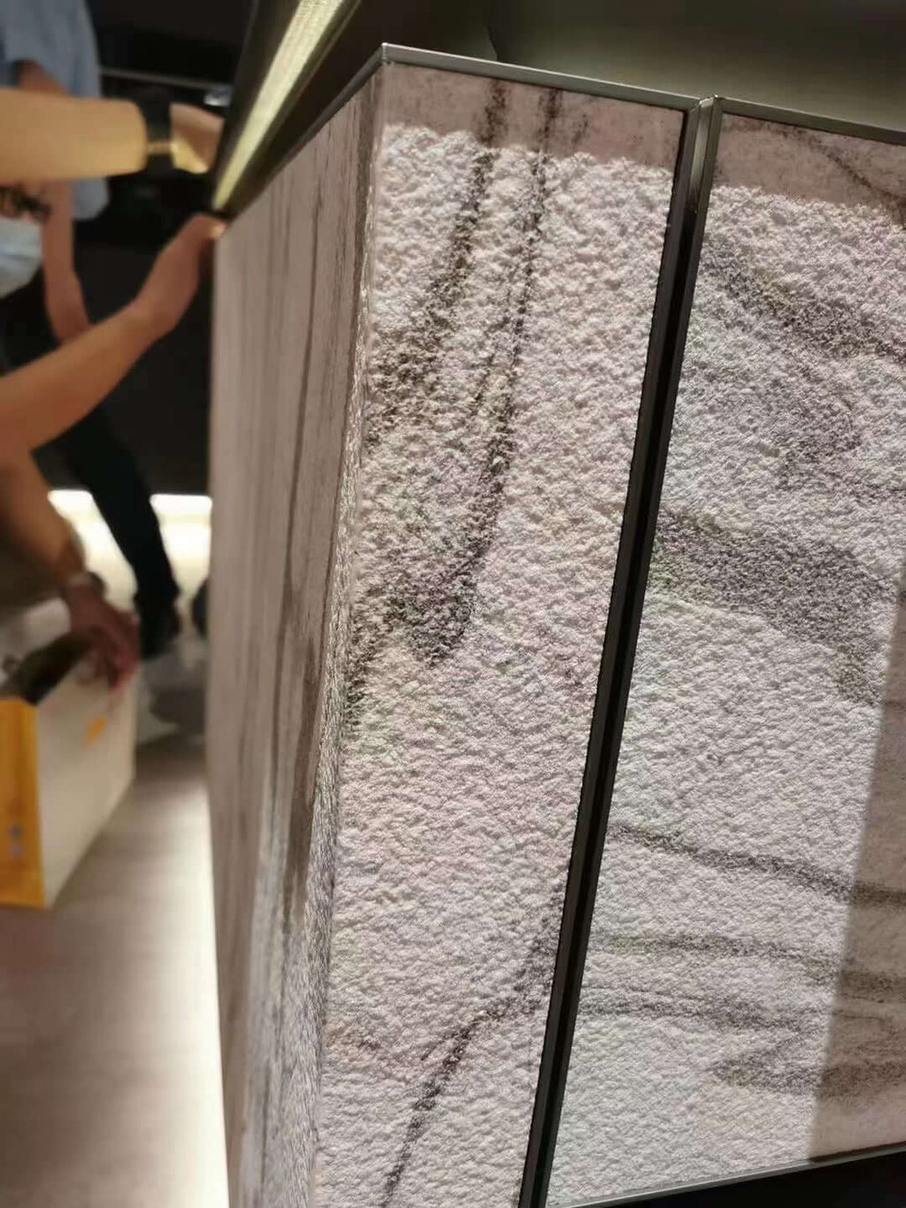 Stone veneer sample boards with white-gray speckled texture inside a display frame
